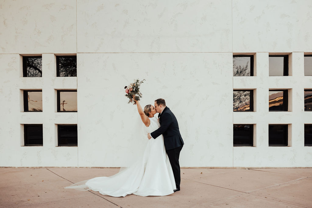 Bride and groom kissing in front of building with windows