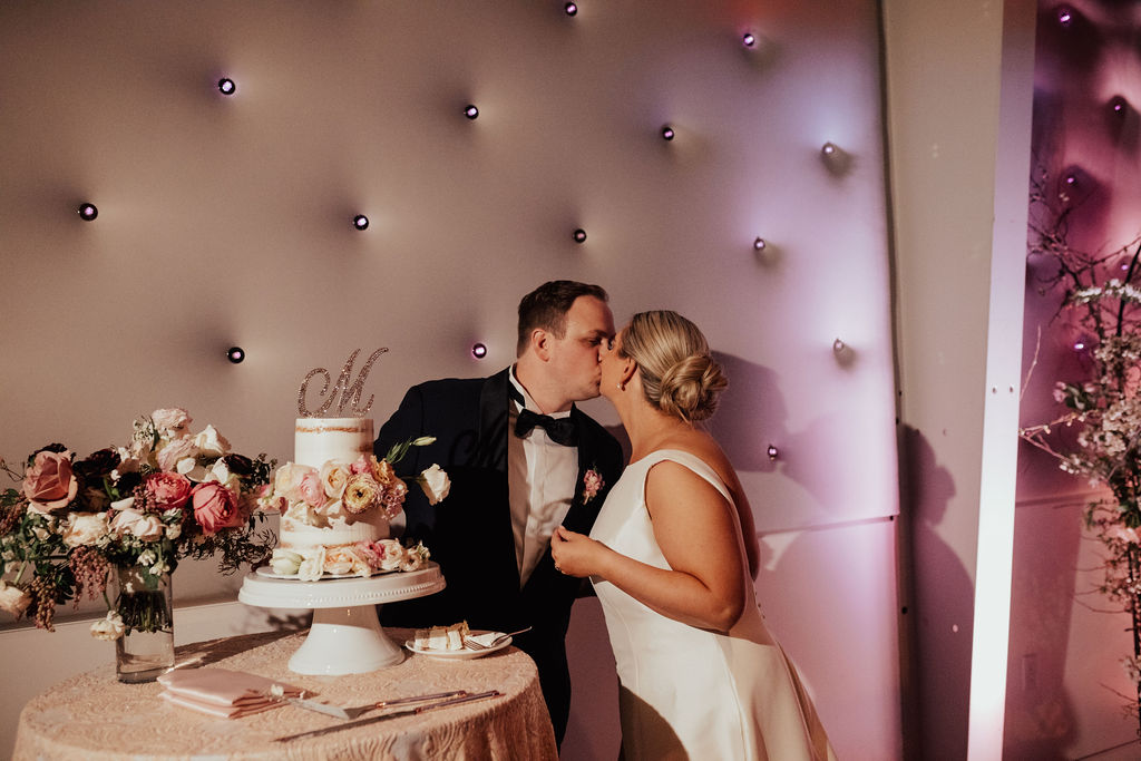 Bride and groom kissing after cutting the cake