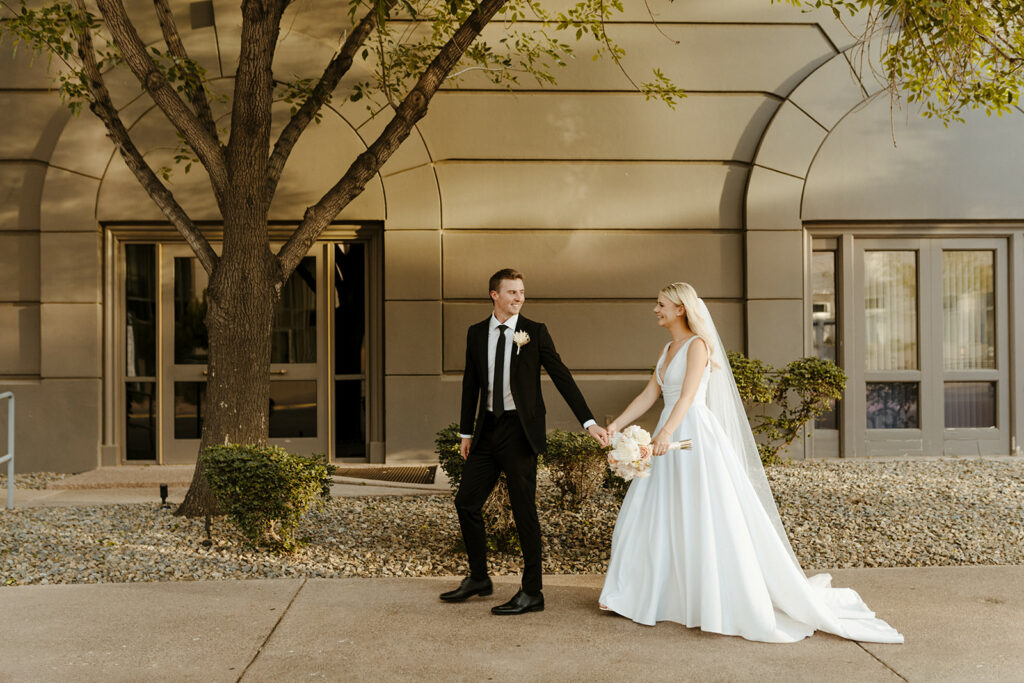 Groom and bride walking in front of building